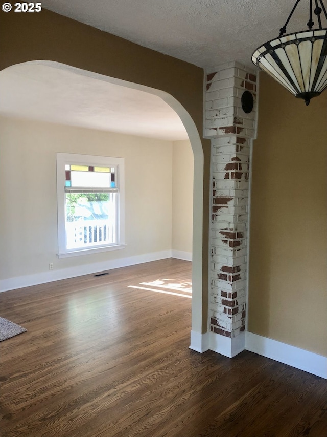 3929 SE 65th Ave, Portland, OR 97206 - empty room with dark wood-style floors, arched walkways, and a textured ceiling