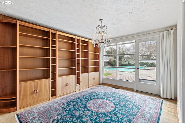 interior space with a chandelier, a textured ceiling, visible vents, and wood finished floors