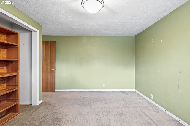 carpeted empty room featuring baseboards and a textured ceiling