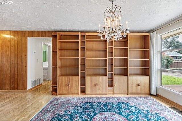 interior space with plenty of natural light, a textured ceiling, visible vents, and wood finished floors