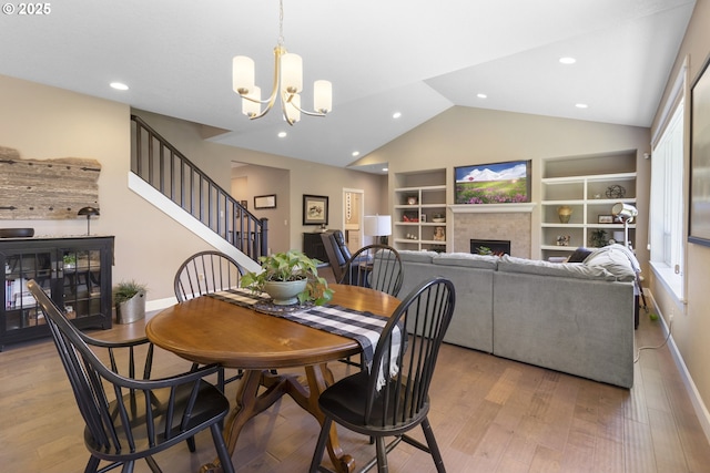 14206 SE Woodside Ave, Milwaukie, OR 97267 - dining area featuring a fireplace, vaulted ceiling, built in features, stairs, and wood finished floors