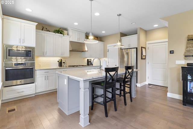 14206 SE Woodside Ave, Milwaukie, OR 97267 - kitchen with appliances with stainless steel finishes, under cabinet range hood, a sink, light wood-style flooring, and recessed lighting