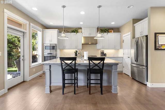 14206 SE Woodside Ave, Milwaukie, OR 97267 - kitchen with stainless steel appliances, tasteful backsplash, a center island with sink, a kitchen breakfast bar, and white cabinetry