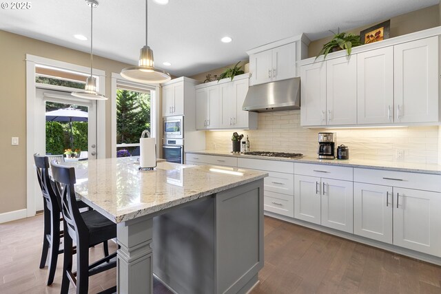 14206 SE Woodside Ave, Milwaukie, OR 97267 - kitchen featuring under cabinet range hood, stainless steel appliances, recessed lighting, decorative backsplash, and a center island