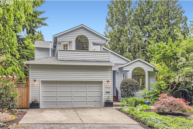 view of front of home with concrete driveway, roof with shingles, an attached garage, and fence