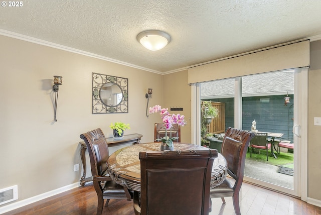 dining room with baseboards, visible vents, wood finished floors, and ornamental molding