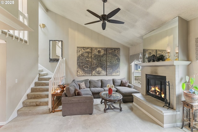 carpeted living room with stairs, vaulted ceiling, a glass covered fireplace, and a healthy amount of sunlight