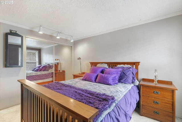 bedroom with a textured ceiling, crown molding, carpet floors, a closet, and track lighting