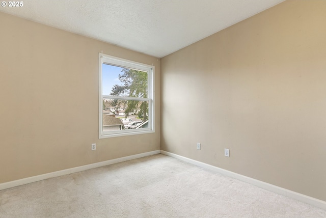 carpeted empty room with a textured ceiling and baseboards