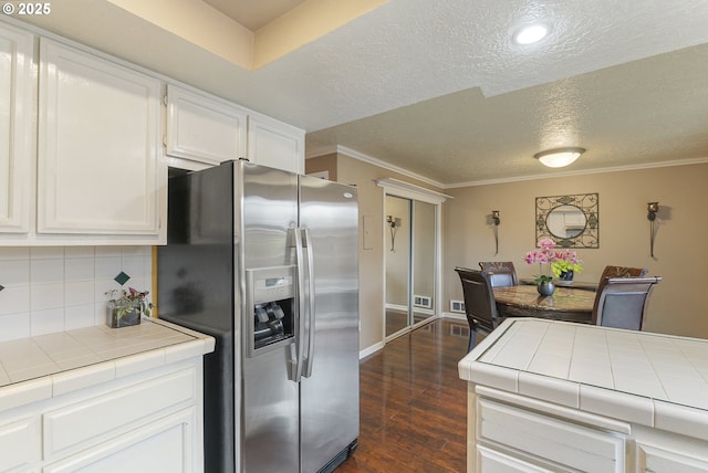 kitchen with tile countertops, stainless steel fridge, and white cabinetry