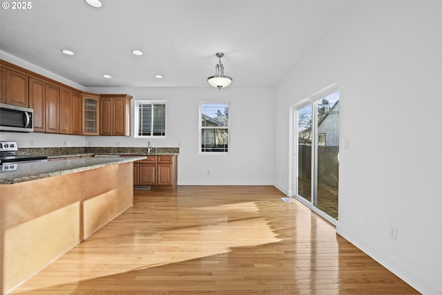 kitchen featuring sink, decorative light fixtures, light hardwood / wood-style flooring, and appliances with stainless steel finishes