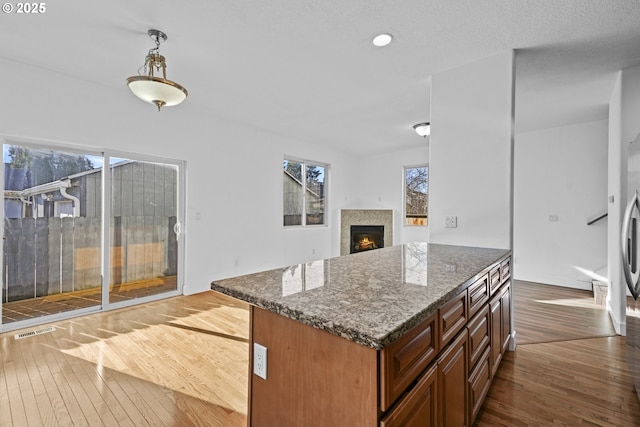 kitchen with hardwood / wood-style flooring, dark stone counters, and pendant lighting