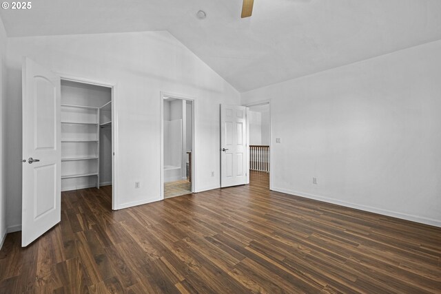 unfurnished bedroom featuring a spacious closet, lofted ceiling, dark wood-type flooring, a closet, and ceiling fan