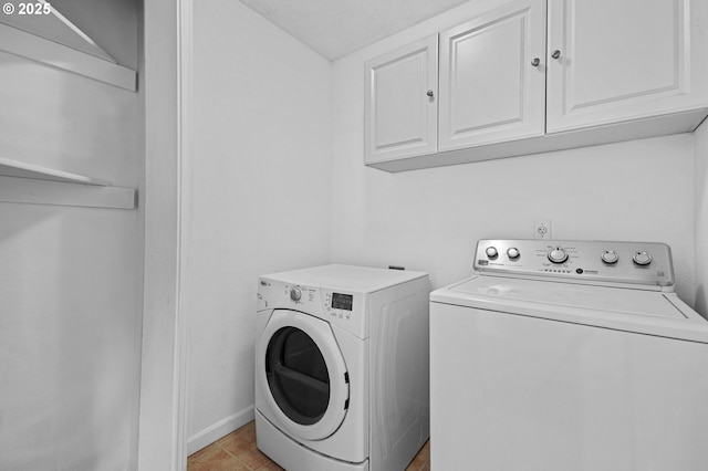 laundry room featuring cabinets, light tile patterned floors, and washing machine and clothes dryer