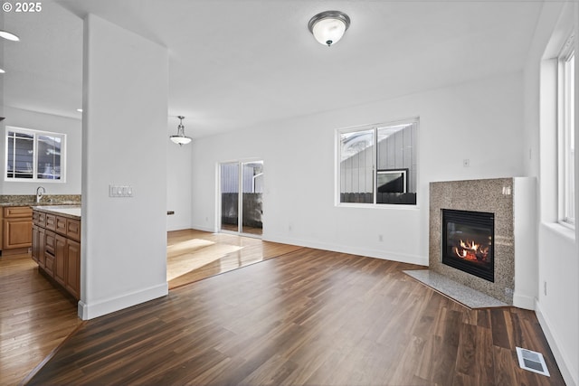 unfurnished living room featuring dark wood-type flooring, plenty of natural light, and a fireplace