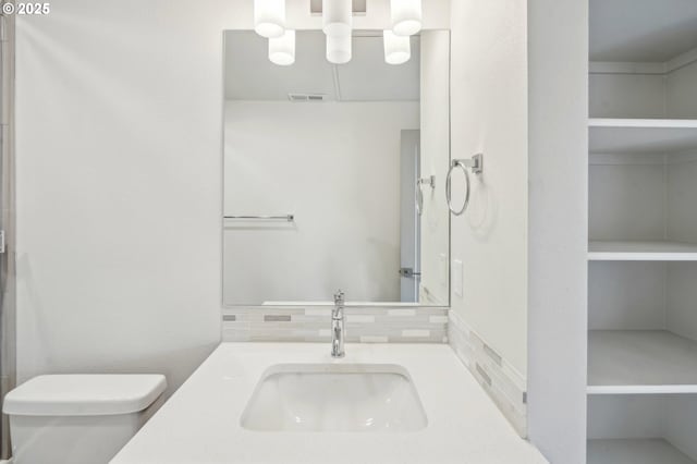 bathroom with toilet, backsplash, and vanity