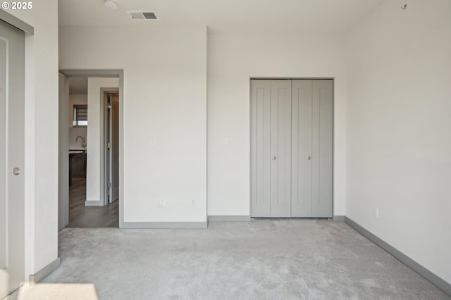 unfurnished bedroom with light carpet, a closet, and sink