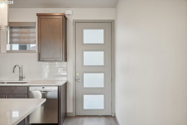 kitchen featuring light hardwood / wood-style floors, stainless steel dishwasher, decorative backsplash, sink, and light stone counters