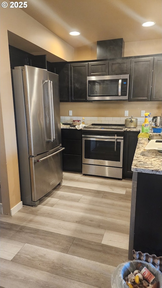 kitchen featuring light stone countertops, appliances with stainless steel finishes, and light hardwood / wood-style floors