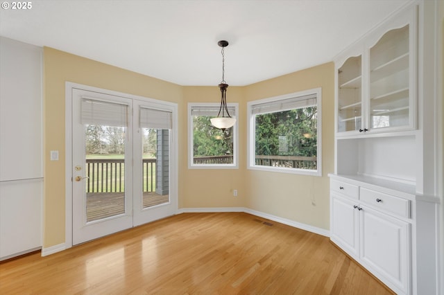 unfurnished dining area featuring light wood-type flooring, visible vents, baseboards, and a healthy amount of sunlight