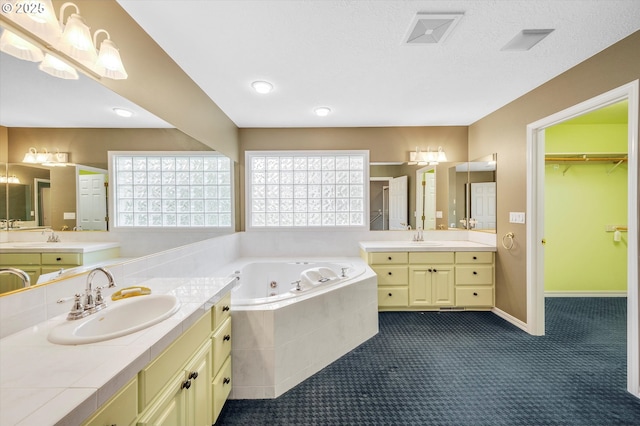 bathroom featuring a sink, baseboards, two vanities, and a jetted tub