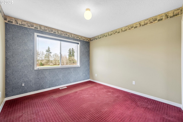 empty room with visible vents, a textured ceiling, baseboards, and dark colored carpet