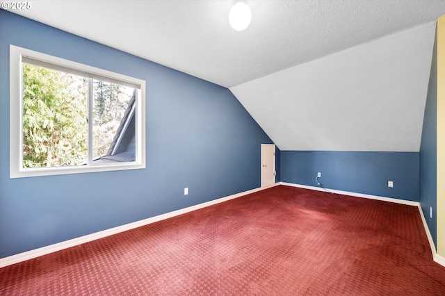 additional living space with vaulted ceiling, a textured ceiling, baseboards, and carpet floors