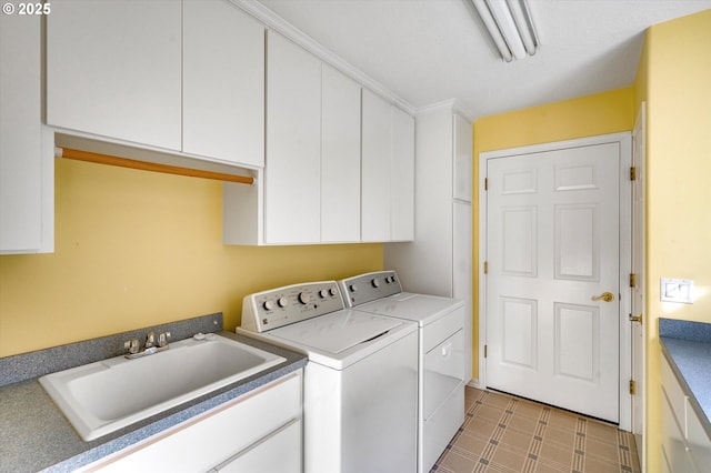 clothes washing area featuring cabinet space, washing machine and dryer, tile patterned floors, and a sink