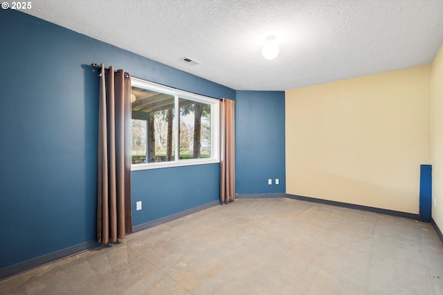 unfurnished room with baseboards, visible vents, and a textured ceiling