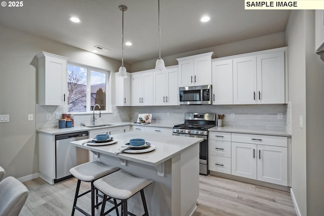17407 SW Atfalati Ln Unit 45, Sherwood, OR 97140 - kitchen featuring stainless steel appliances, a sink, light wood-type flooring, white cabinetry, and backsplash