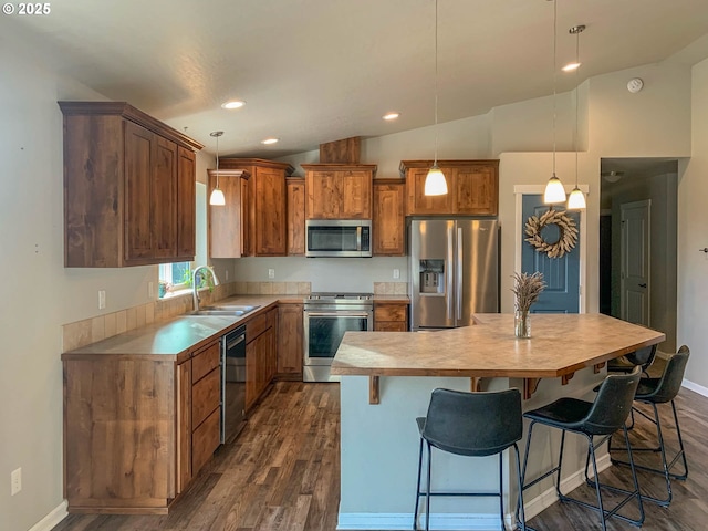 kitchen with appliances with stainless steel finishes, decorative light fixtures, sink, and a kitchen island