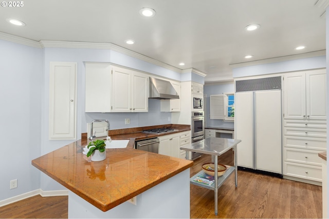 3925 SW Humphrey Blvd, Portland, OR 97221 - kitchen with built in appliances, wall chimney exhaust hood, crown molding, a peninsula, and recessed lighting