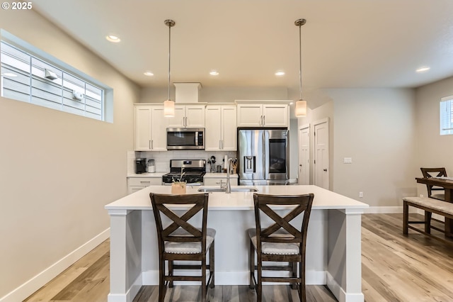 4451 SE Hardwood Ln, Hillsboro, OR 97123 - kitchen featuring stainless steel appliances, a sink, light countertops, an island with sink, and light wood finished floors
