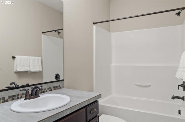 bathroom featuring  shower combination, toilet, vanity, and backsplash