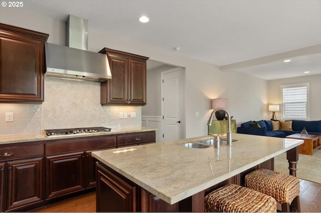 kitchen featuring wall chimney exhaust hood, a sink, stainless steel gas stovetop, wood finished floors, and recessed lighting