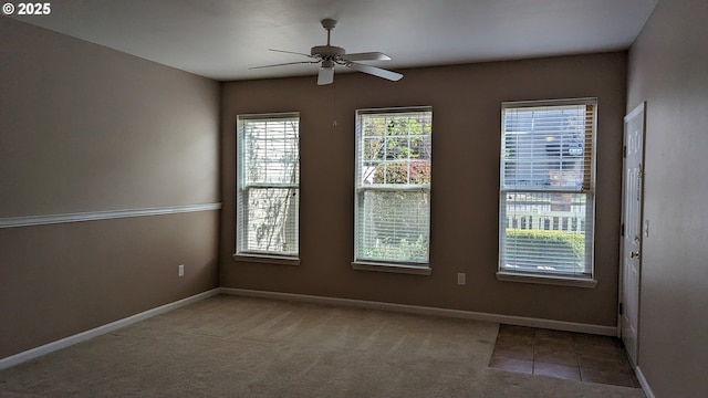 empty room with carpet floors, a ceiling fan, and baseboards