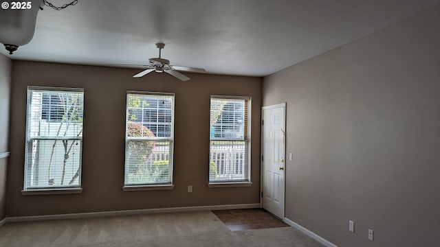 empty room featuring a ceiling fan, baseboards, and carpet