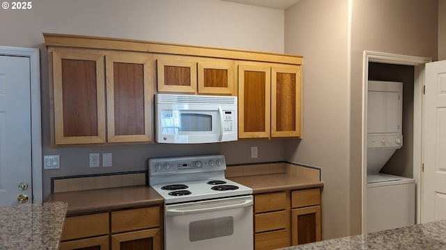 kitchen featuring stacked washing maching and dryer, light stone countertops, and white appliances