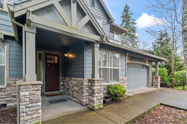 view of exterior entry featuring a garage, stone siding, and driveway