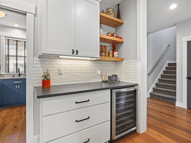 bar featuring sink, light hardwood / wood-style flooring, white cabinets, blue cabinets, and beverage cooler