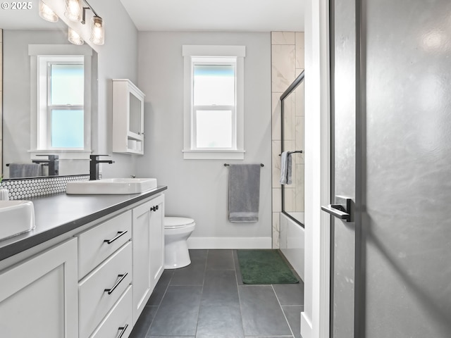 full bathroom featuring toilet, plenty of natural light, shower / bath combination with glass door, and tile patterned flooring