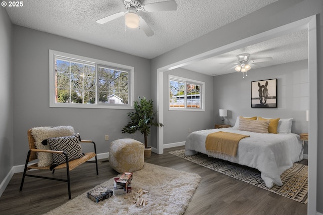 bedroom with ceiling fan, a textured ceiling, baseboards, and wood finished floors