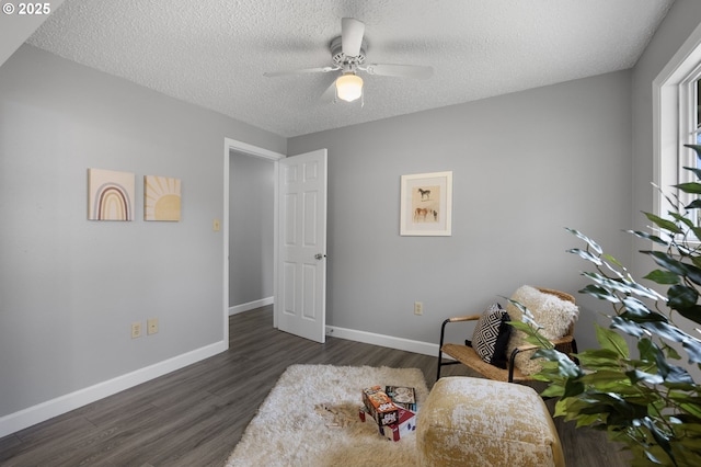 sitting room featuring a textured ceiling, a ceiling fan, dark wood-type flooring, and baseboards