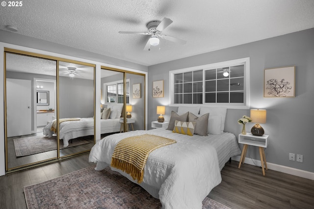 bedroom featuring baseboards, two closets, wood finished floors, and a textured ceiling