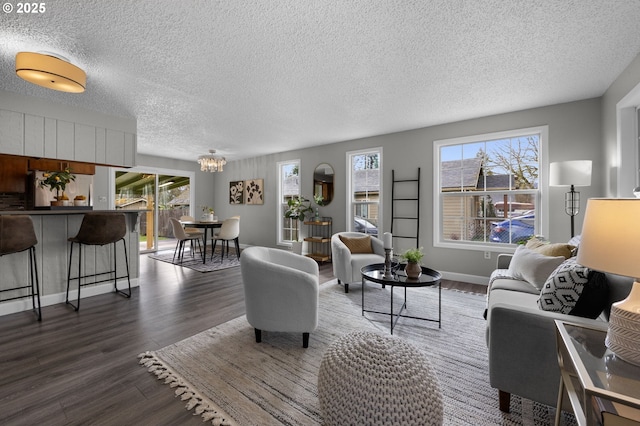 living area featuring a notable chandelier, wood finished floors, plenty of natural light, and baseboards