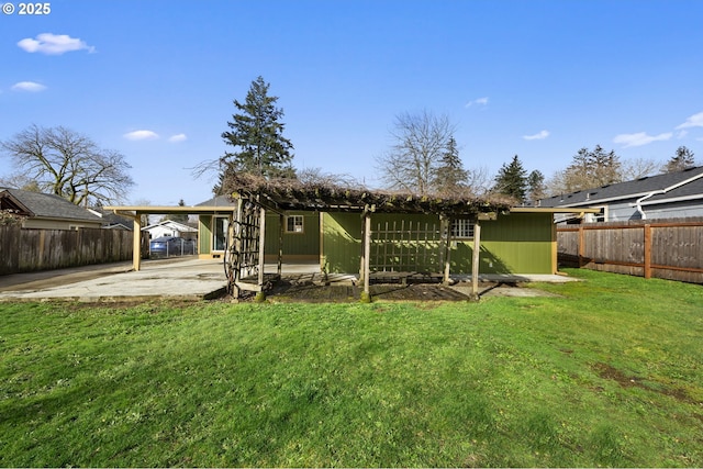 rear view of property with a patio, a lawn, a fenced backyard, and a carport