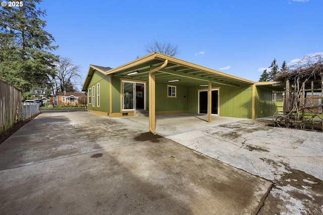 back of house featuring an attached carport, driveway, and fence