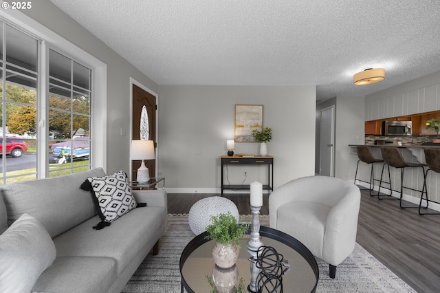 living area with baseboards, a textured ceiling, and wood finished floors