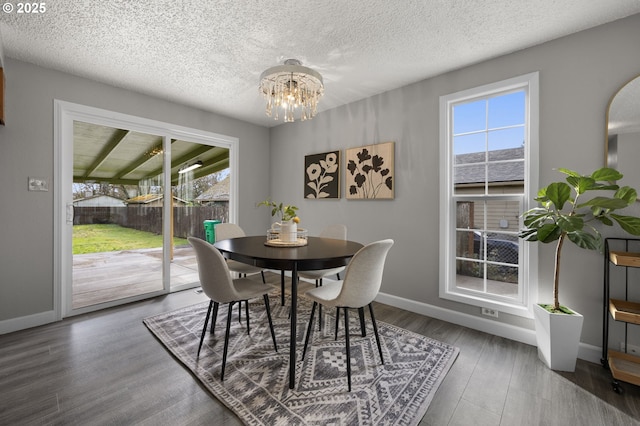 dining area with a healthy amount of sunlight, baseboards, an inviting chandelier, and wood finished floors