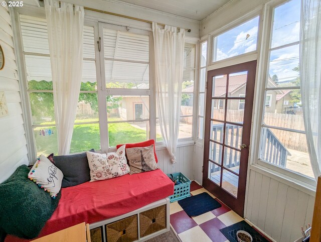 sunroom with tile patterned floors and wood walls